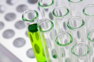 Multiple test tubes in a holder. One contains a green liquid