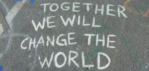 Chalk writing on pavement that says "Together we will change the world"